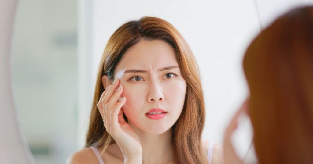 鏡を見ながら肌の状態に悩む女性。引き寄せ美容で結果が出ないと感じている人の様子。