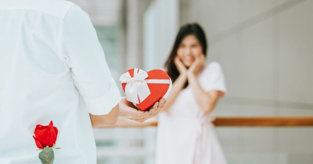 引き寄せの法則で電撃結婚を叶えたい男性が、サプライズでハート型のプレゼントを贈ろうとしている場面