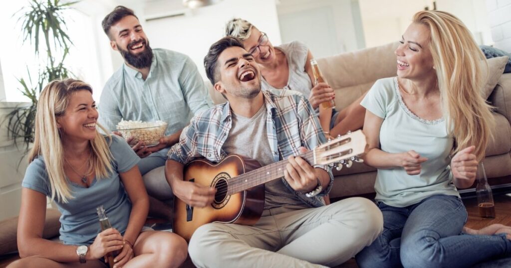 楽しそうにギターを弾きながら笑い合う若者たちのグループ