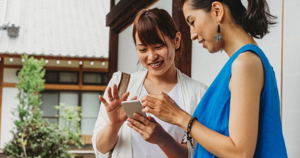 引き寄せの成功体験をスマホで共有する2人の女性