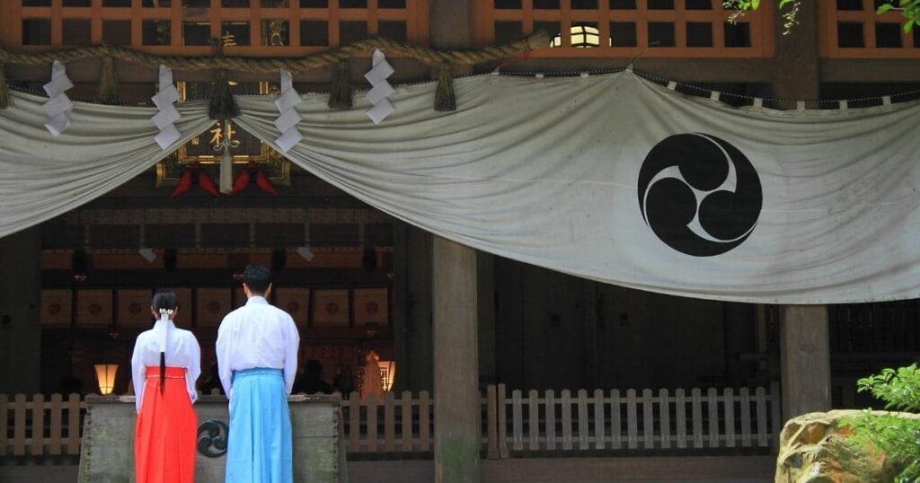 緑豊かな背景に立つ伝統的な神社の建物。金運アップにおすすめのパワースポットの風景