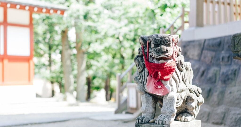 神社に鎮座する狛犬。赤い布をまとっており、厳かな雰囲気を醸し出している。
