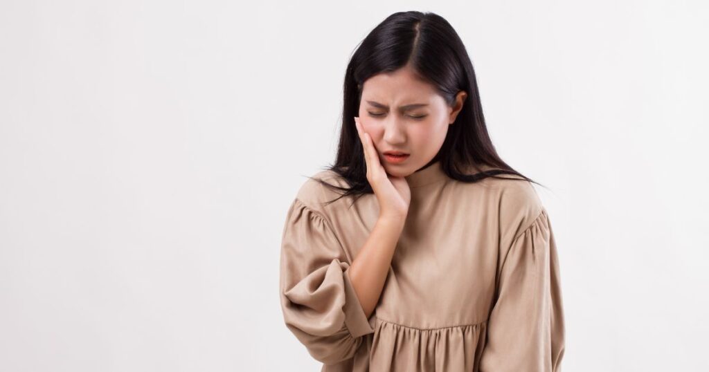 虫歯の痛みに悩む女性。引き寄せの法則と虫歯の関係を考察するスピリチュアル記事の冒頭イメージ。