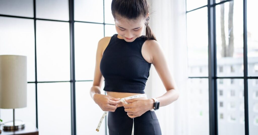 理想体型に近づき、笑顔でウエストを測る引き寄せダイエット実践中の女性