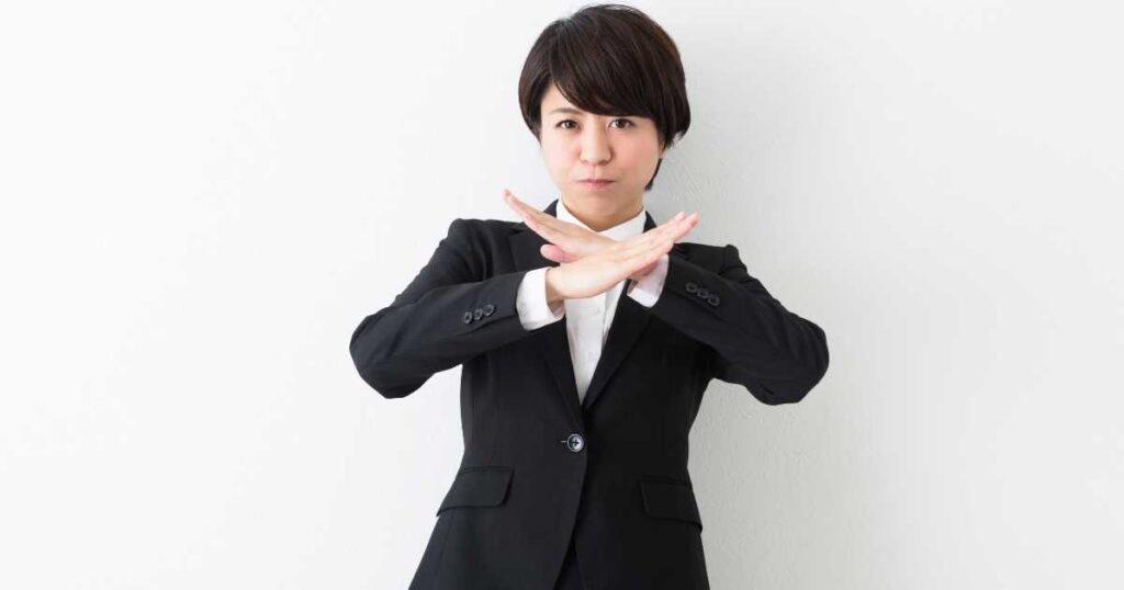 金運を妨げるNG習慣を象徴するスーツ姿の女性が注意喚起する姿